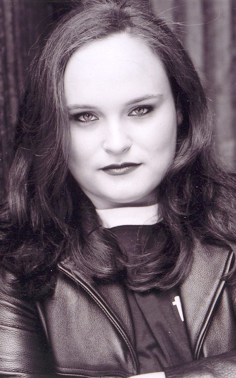 A sepia toned image of a light skinned woman with dark hair wearing a leather jacket, from the chest up